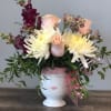 Bouquet of white and blush flowers in a white face vase