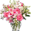 Pink roses and lilies arranged in a clear glass vase