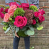 Bouquet of hot pink and blush roses in a green glass vase