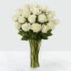 Tall clear vase of long-stem white roses arranged in a rounded cluster