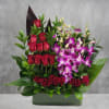 Red roses and purple orchids arranged in a rectangular vase