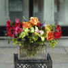 Colorful bouquet of orange roses and red flowers in a glass vase