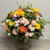 Colorful arrangement of pink roses and mixed bright blooms in a ribbed glass cylinder vase