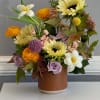 Mixed bouquet of sunflowers, roses, and white daffodils in a textured vase