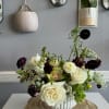 White and dark burgundy floral arrangement in a ribbed white vase