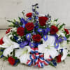 Patriotic red, white, and blue floral arrangement with roses, lilies, and ribbon bow