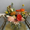 Mixed bouquet in a clear glass vase with orange and blush flowers