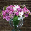Pink rose bouquet with white orchids in a clear glass vase
