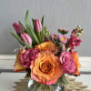 Pink tulips and orange roses arranged in a glass vase