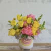 Yellow tulips and pink flowers in a white ceramic vase