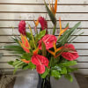 Tall tropical arrangement with red anthurium and orange bird-of-paradise in a black vase