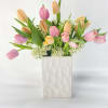 Pink and peach tulips arranged in a white textured vase