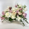 Pastel rose bouquet in a white vase with trailing greenery