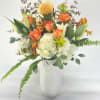 Orange and white floral arrangement in a white vase