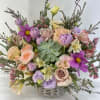 Mixed pastel bouquet in a woven basket with roses and tulips