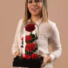 Woman holding three red roses under a glass dome on a black base