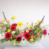 Vibrant red gerbera daisies, buttery yellow blooms, soft pink accents, and crisp