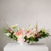 Layers of blush hydrangea, peach and coral roses, and delicate ranunculus unfold