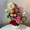 Mixed bouquet of roses, ranunculus, and snapdragons in a white bowl vase