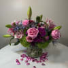 Pink roses and lilies arranged in a glass vase with heart confetti