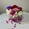 Bouquet of red, pink, white, and purple flowers in a pink vase with heart confetti
