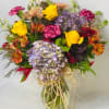 Mixed bouquet of roses, hydrangeas, and carnations in a glass vase