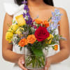 Woman holding a colorful mixed bouquet in a glass vase