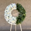 White floral wreath with cream roses on a wooden easel