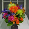Colorful mixed bouquet in a dark vase with orange, purple, pink, and green blooms