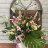 Pink and white lilies arranged in a white vase with a plaid ribbon.
