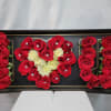 Red and white roses arranged in a black display box spelling 