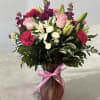 Pink and white mixed flower bouquet in a pink vase with a ribbon