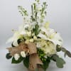White lilies and roses arranged in a burlap-wrapped box
