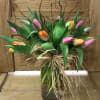 Bouquet of multicolored tulips in a glass vase with raffia bow
