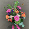 Bright pink gerberas, orange and pale spray roses, coral carnations and purple