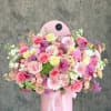 Large pink floral arrangement in a round pink box with a lace ribbon