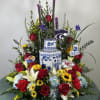 Large floral arrangement with roses, lilies, and sunflowers around a blue-and-white vase
