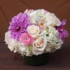 Pink, white, and purple flower arrangement in a dark vase