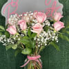 Pink roses and baby's breath in a clear vase with a pink ribbon