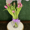Pink tulips in a clear glass vase with a lavender ribbon