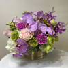 Purple orchids with pink roses and green carnations in a gold container