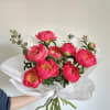 Bouquet of bright pink peonies wrapped in white paper