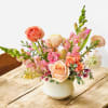 Pastel flower arrangement in a white vase on a wooden table