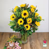 Sunflower bouquet in a clear glass vase with a small pink tropical flower cluster beside it