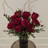 Deep red roses arranged in a black vase with curly branches