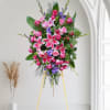 Standing floral spray with pink lilies and roses on a gold easel
