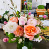 Mixed pink and peach flowers arranged in a green glass vase