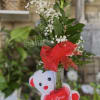 Single red rose in a glass vase with a teddy bear and heart decoration