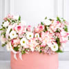 Pink and white roses arranged in a round pink box with ribbon
