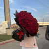 Large bouquet of red roses wrapped in black paper with a red ribbon